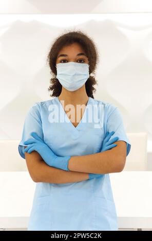 Junge müde überarbeitete afroamerikanische medizinische Arbeiter tragen Gesichtsschutzmaske, die mit frustrierten Ausdruck auf die Kamera schaut. Gesundheitswesen Stockfoto