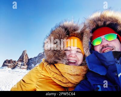 Selfi-Porträt eines glücklichen Paares auf dem gefrorenen Wintersee Baikal. Durchsichtiges Eis. Reisen im Winter, aktive Erholung, Sport, Urlaub Stockfoto