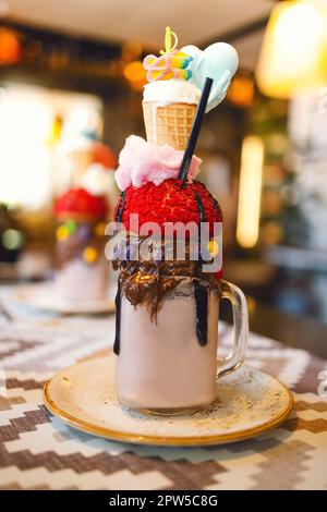 Schokoladenmilchshake mit Eis und Schlagsahne, Marshmallows, süße Kekse, Waffeln, serviert in einem Glasmauerwerk. Freak oder verrückter süßer Cocktail Stockfoto