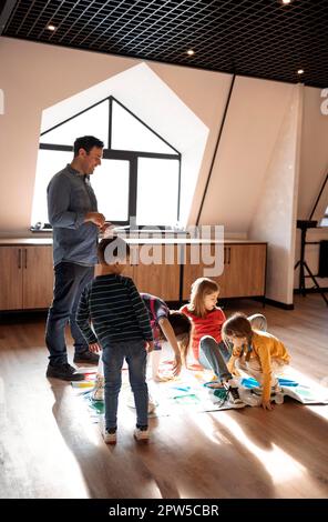 Glückliche große Familie mit Spaß zusammen, Kinder mit Vater spielen Twister Spiel zu Hause. Familienaktivitäten Stockfoto