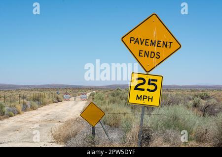 Ein Schild in der Mojave-Wüste bei Lancaster, Kalifornien, warnt davor, dass der Bürgersteig vor uns endet. Hinter dem Tor befindet sich der Luftwaffenstützpunkt Edwards. Stockfoto