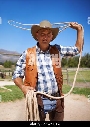 Er zeigt seine Fähigkeiten mit einem Lasso. Ein Mann mit Lasso auf der Farm Stockfoto