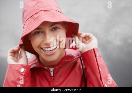 Ich bin bereit für den Regen. Eine attraktive junge Frau, die im Regen steht Stockfoto