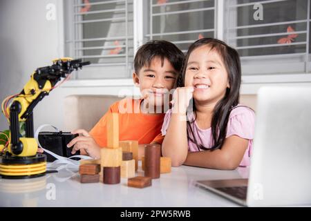 Zwei Kinder programmieren und testen Roboter ARM ihre Wissenschaft, Kid kleines Mädchen Programm Code zu Roboter mit Laptop-Computer und der Junge testen mit Fernbedienung Stockfoto