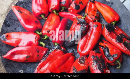 Rösten Sie köstliche rote Paprika für einen rauchigen Geschmack und schnelles Schälen. Balkansalatrezepte. Thermische Verarbeitung der Pfefferpflanze auf einem Metallkreis. Pe Stockfoto