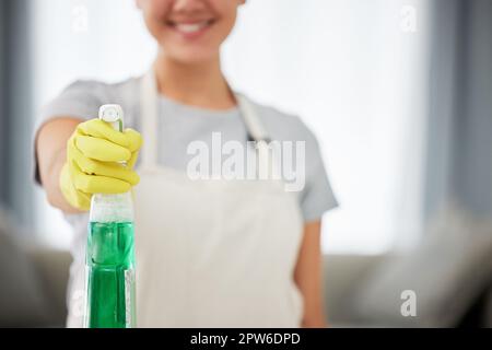 Eine unkenntliche Frau, die ein Reinigungsprodukt in der Hand hält, während sie ihre Wohnung reinigt. Ein unbekannter Haushaltsreiniger, der Latexreinigungshandschuhe trägt. Stockfoto