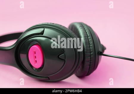 Schwarz Kopfhörer liegt auf einem farbenfrohen Pastelltönen rosa Hintergrund. Musik Konzept Stockfoto