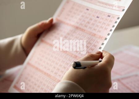 Ausfüllen eines Lottoscheines. Eine junge Frau spielt im Lotto und träumt davon, den Jackpot zu gewinnen. Spielkonzept Stockfoto