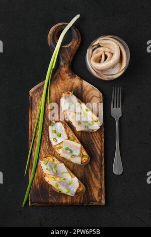 Blick von oben auf das Sandwich mit salzigem Hering und Frühlingszwiebeln Stockfoto