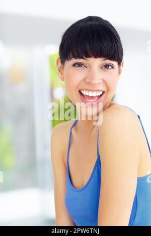 Sie hat eine sonnige Einstellung. Eine reizende junge Frau, die lacht und ein großes Lächeln schenkt Stockfoto