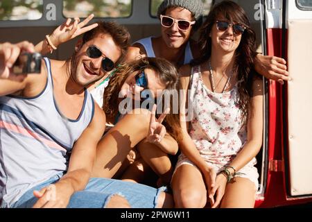 Freunde für immer. Vier Freunde, die in der Sommersonne um ein Schnappschuss-Foto herumspielen Stockfoto