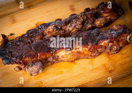 Gebratene Schweinerippchen mit Barbecue-Sauce auf Holzbrett. Kopierraum. Stockfoto
