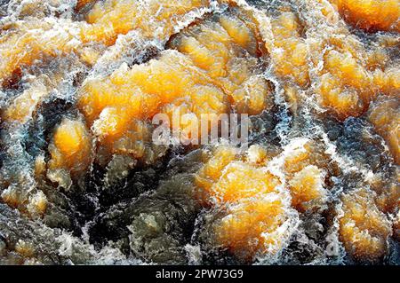 Das schräge Sonnenlicht scheint durch das sprudelnde Wasser eines Flusses mit Stromschnellen Stockfoto