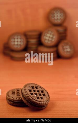 Haufen Chocolate Chip Cookies mit Weiße Vanille Creme gefüllt liegt auf Holz- braune Oberfläche. Süßes und leckeres Sandwich runde Kekse. Detaillierte essen Ph Stockfoto