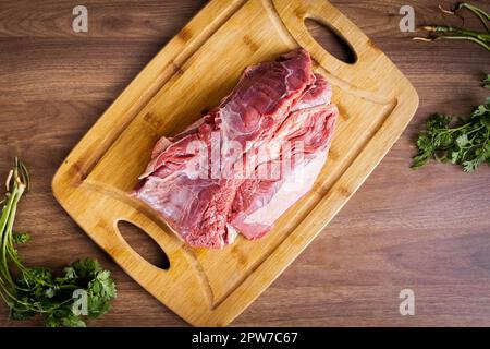 FLANK STEAK Beef BBQ Essen. Mit Fett bedecktes rohes Fleisch auf einem Holzbrett auf einem Holzhintergrund. Gewürzt mit Koriander. Stockfoto