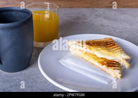 Gegrillter Schinken und Käse. Sandwich mit Käse und Schinken auf dem Grill. In zwei Hälften serviert. Serviert mit Kaffee mit Milch und Orangensaft. Stockfoto