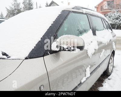 Schnee und Eis auf der Windschutzscheibe, den Rückspiegeln des Fahrzeugs. Winterliche Fahrbedingungen. Schneeräumen. Strassenverkehr im Winter. Metall Stockfoto