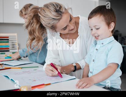 Familienunterricht zu Hause. Mutter hilft Sohn bei Hausaufgaben während der Quarantäne. Ein kleiner Junge, der malt und Spaß hat, eine Fernausbildung zu bekommen Stockfoto