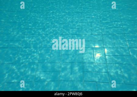 Schwimmbad unten, Sonne am blauen Kacheln, Linien durch Wasser Lichtbrechung verzerrt. Stockfoto