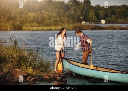 Jede Kanufahrt bringt sie näher heran. Ein junges Paar, das eine Kanufahrt auf dem See macht. Stockfoto