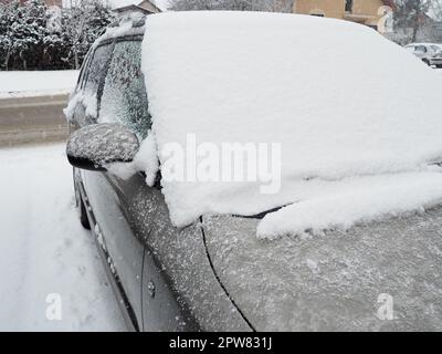 Schnee und Eis auf der Windschutzscheibe, den Rückspiegeln des Fahrzeugs. Winterliche Fahrbedingungen. Schneeräumen. Strassenverkehr im Winter. Metall Stockfoto