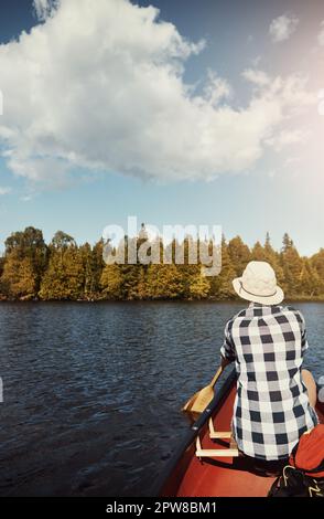 Schwebend in der Natur. Eine attraktive junge Frau, die einen Tag mit dem Kajak auf dem See verbringt. Stockfoto