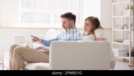 Familienpaar, Das Den Laptop Auf Dem Sofa Online Nutzt Stockfoto