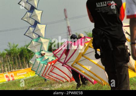 Männer, die während des 2004 Jakarta International Kite Festivals, das am 9-11. Juli am Karnaval (Karneval) Beach in Ancol Dreamland, North Jakarta, Jakarta, Indonesien, stattfand, einen riesigen Drachen fliegen. Stockfoto