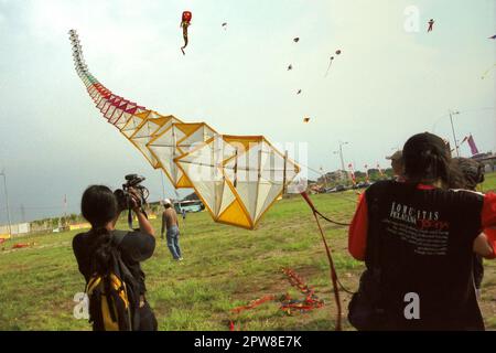 Männer, die während des 2004 Jakarta International Kite Festivals, das am 9-11. Juli am Karnaval (Karneval) Beach in Ancol Dreamland, North Jakarta, Jakarta, Indonesien, stattfand, einen riesigen Drachen fliegen. Stockfoto