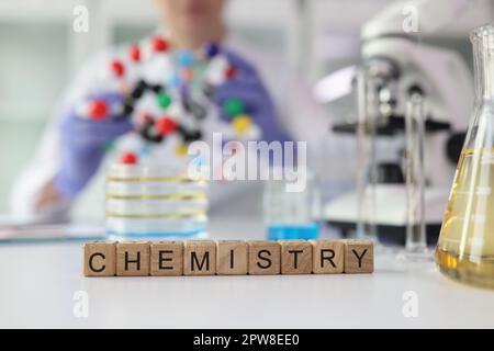 Word Chemistry aus Würfeln in der Nähe von Laborglasgeräten Stockfoto