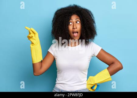Attraktive junge Frau, isoliert auf blauem Hintergrund, mit positivem Überraschungsgesicht und mit dem Finger auf den Kopierraum zu zeigen. Stockfoto
