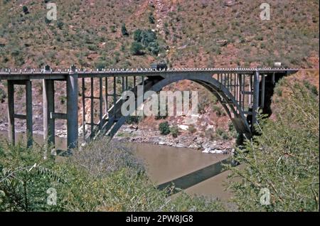 Ein Blick aus dem Jahr 1974 auf die elegante Betonbrücke über die Blue Nil (Abay) Gorge mit einem LKW, der über sie fährt. Es liegt in der Nähe der Stadt Goha Tsion in Äthiopien. Eine kürzlich fertiggestellte japanische Brücke befindet sich nun neben dieser Brücke. Die ältere Brücke wird heute nur noch von Fußgängern genutzt, während die japanische Brücke den Äthiopischen Nationalstraße 3 zwischen Addis Abeba und Bahir dar führt. Der Blaue Nil bildet die Grenze zwischen den Regionen Amhara und Oromia. Dieses Bild stammt von einer alten Amateur-35-mm-Farbdurchlässigkeit – ein Vintage-Foto aus den 1970er Jahren. Stockfoto