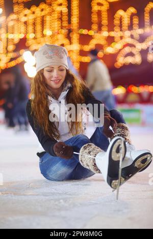 Schlittschuhlaufen, Happy und Woman binden Schuhe auf der Eisbahn für Fitness, Training und Workout in der Nacht. Skater, Lächeln und weibliche Person, die Schlittschuhschnürsenkel für bindet Stockfoto