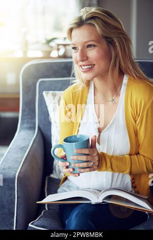 Es geht nichts über eine gute Lektüre, um den Tag zu verschönern. Eine junge Frau, die eine Tasse Kaffee trinkt, während sie ein Buch liest. Stockfoto