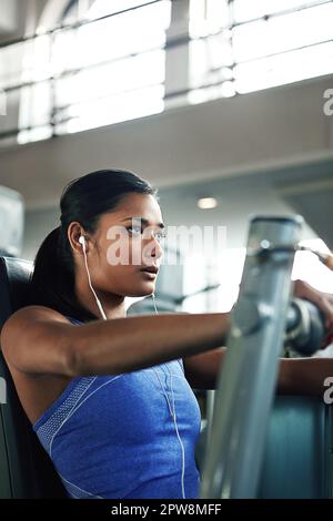Nichts hält sie von guter Gesundheit ab. Eine junge Frau, die mit einer Brustpresse im Fitnessstudio trainiert. Stockfoto