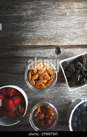 Glutenfreie Leckereien. Aus einem großen Winkel mit einer Auswahl an Nüssen und Beeren auf einem Tisch. Stockfoto