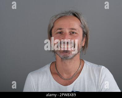 Das kaukasische männliche, reife Porträt. Männlich mit gelben Zähnen. Lächelnder Mann mit ungesunden Zähnen. Unordentlicher Haarmann Stockfoto