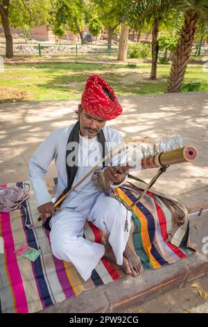 Ein Mann, der ein traditionelles Musikinstrument in authentischer einheimischer Kleidung auf der Straße von indien spielt, wird am Morgen am 11 202. April mit jodhpur rajasthan india aufgenommen Stockfoto
