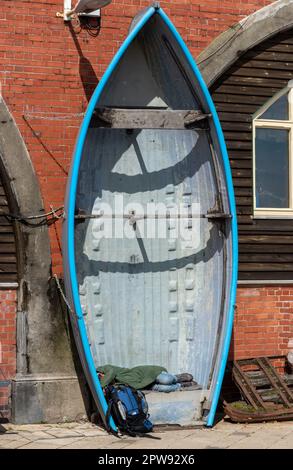 Schlafen in einem Boot am Meer in Brighton, vielleicht ein Obdachloser, der ein Nickerchen macht. April 2023 Stockfoto