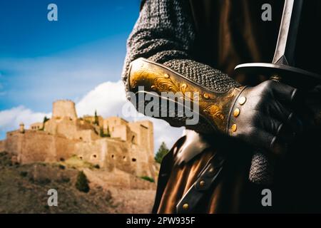 Ein mittelalterlicher Ritter, der ein Schwert hält, mit dem Schloss Cardona im Hintergrund. Stockfoto