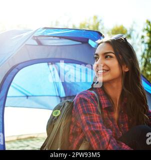 Sie entkommt allem. Eine attraktive junge Frau, die auf ihrem Campingplatz sitzt. Stockfoto