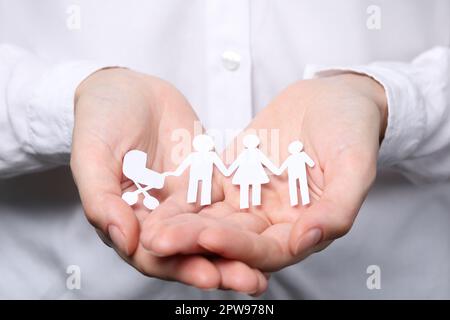 Eine Frau, die Familienfiguren in Papierform hält, Nahaufnahme. Versicherungskonzept Stockfoto