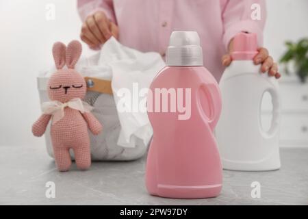 Frau mit Kleider am Tisch, konzentriere dich auf eine Flasche Waschmittel Stockfoto