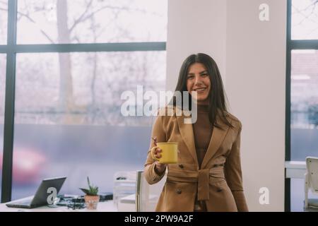 Nahaufnahme einer wunderschönen braunen Geschäftsfrau, die lächelt und direkt in die Kamera schaut, während sie im CO-Arbeitsbereich steht Stockfoto