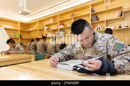 (230429) -- KHUNJERAB, 29. April 2023 (Xinhua) -- Soldaten lesen Bücher in einem Leseraum in der Baracke in Khunjerab, Nordwestchina, Uygur Autonomer Region Xinjiang, 13. April 2023. Gao Guanghui, ein Rekrut, der erst seit 7 Monaten der Armee beigetreten war, war schockiert, als er den Ehrenraum des Grenzverteidigungsregiments in Khunjerab im Nordwesten Chinas Uygur Autonomer Region Xinjiang betrat. Das Regiment basiert auf den Pamiren und bewacht die China-pakistanische Grenze und den Hafen von Khunjerab. Mit einer durchschnittlichen Höhe von 4.700 Metern ist der Ort eine „verbotene Zone“ für viele Menschen, wie die Temperatur Stockfoto