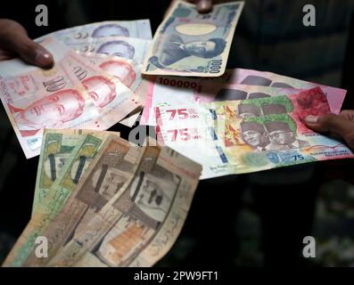 Asiatisches Kind mit indonesischem Rupien, Singapur-Dollar, Saudi-Arabien-Rial und Japan-Yen-Geld, ausgewählter Fokus Stockfoto