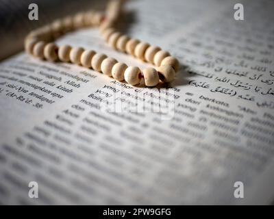 Weißer tasbih, Gebetsperlen auf einem islamischen Buch, ausgewählter Fokus Stockfoto