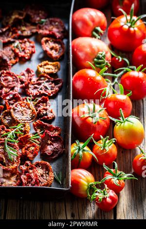 Hausgemachte und frische, als aromatische Zutaten getrocknete Tomaten. Getrocknetes Gemüse in der Sonne im Garten. Stockfoto