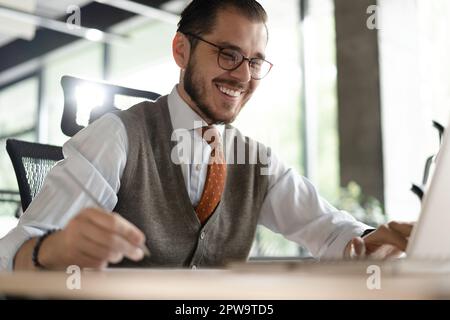 Geschäftsmann aus dem modernen Büro, der am Computer arbeitet. Porträt eines erfolgreichen IT-Software-Ingenieurs mittleren Alters, der an einem Laptop an seinem Schreibtisch arbeitet Stockfoto