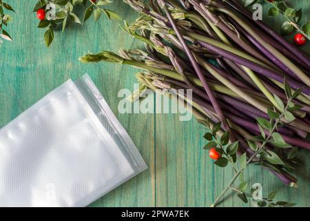 Sprossen von Metzgerbesen, isoliert auf grünem Hintergrund. Ruscus Aculeatus frische Sprossen, die unter Vakuum gestellt werden Stockfoto